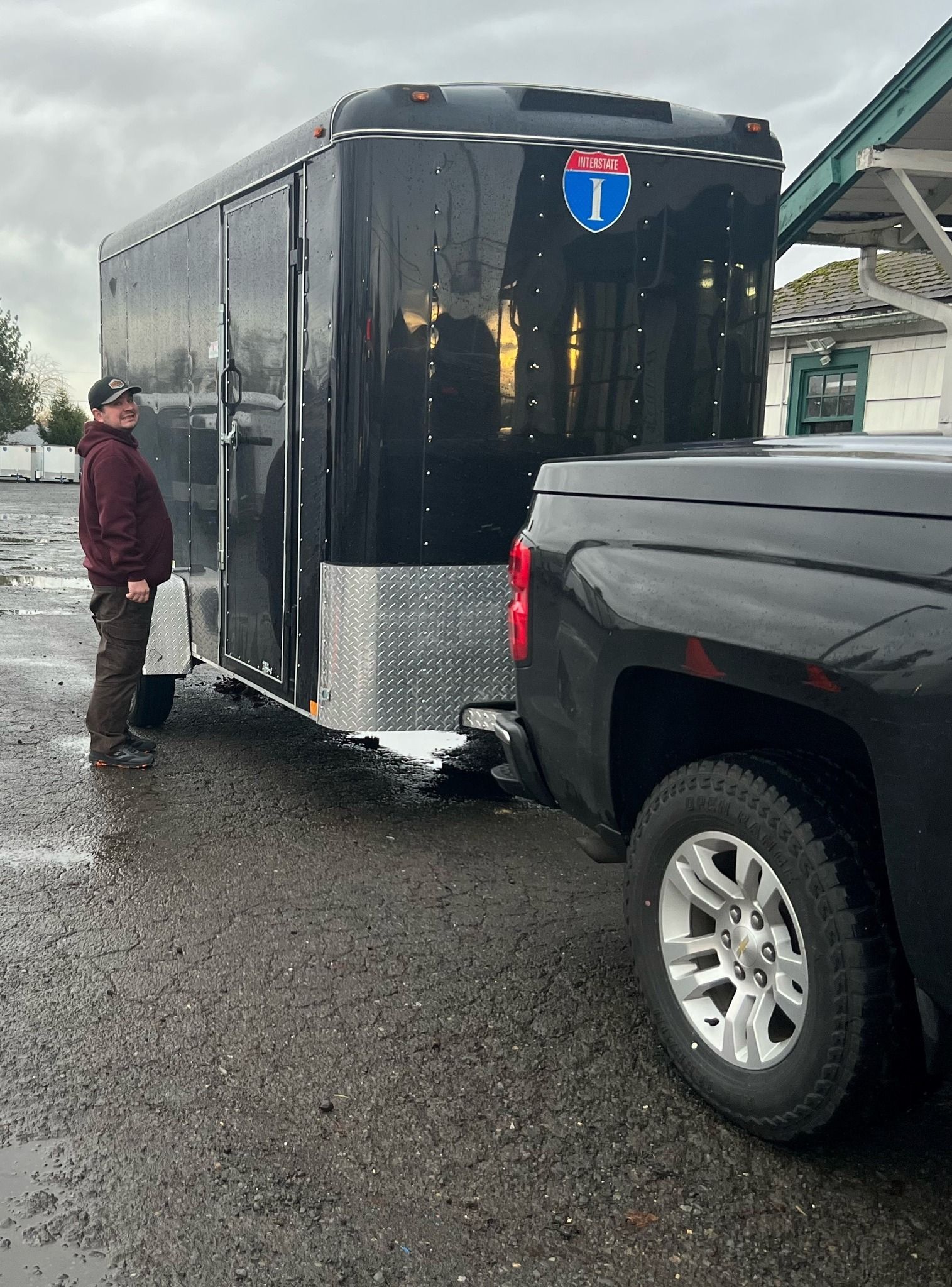 A man is standing next to a trailer that is being towed by a truck.
