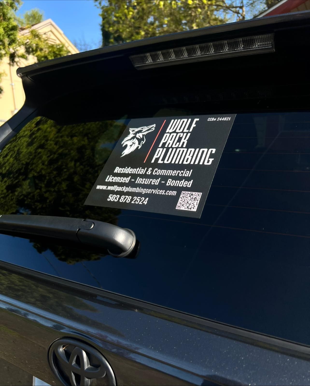 A car with a sticker on the back window that says `` wolf pack plumbing ''.