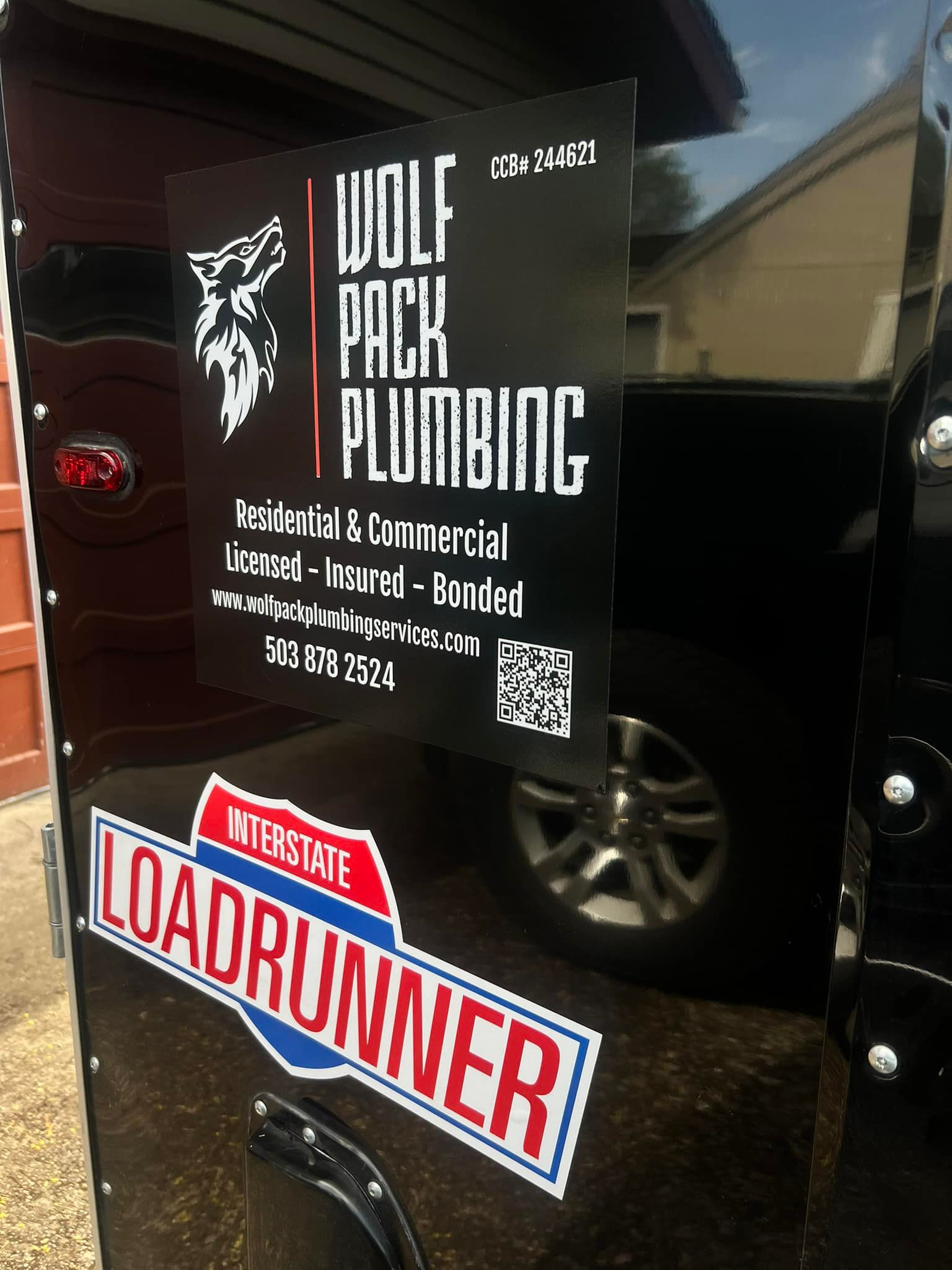 A wolf pack plumbing sign is on the side of a trailer