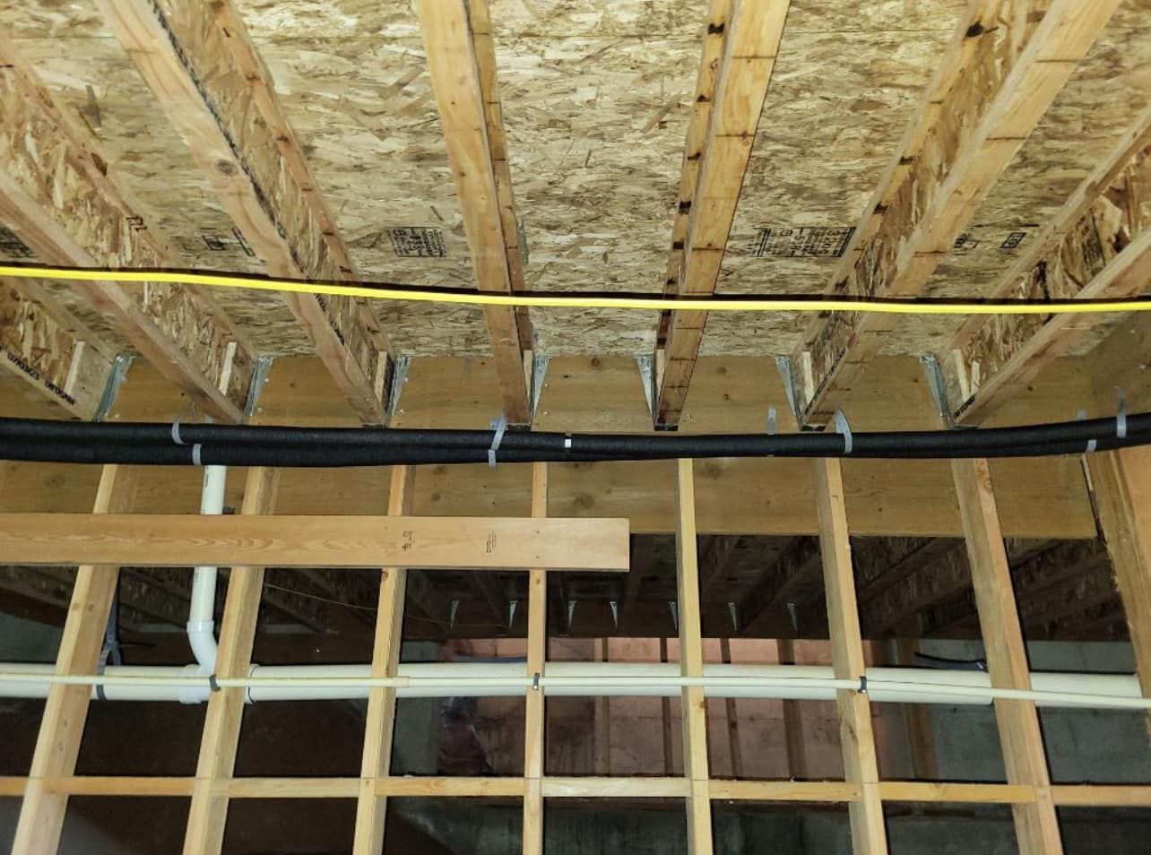 A pipe is hanging from the ceiling of a building under construction.
