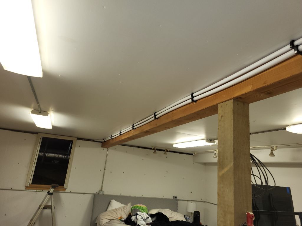 A cat is laying on a bed in a room with a wooden beam hanging from the ceiling.