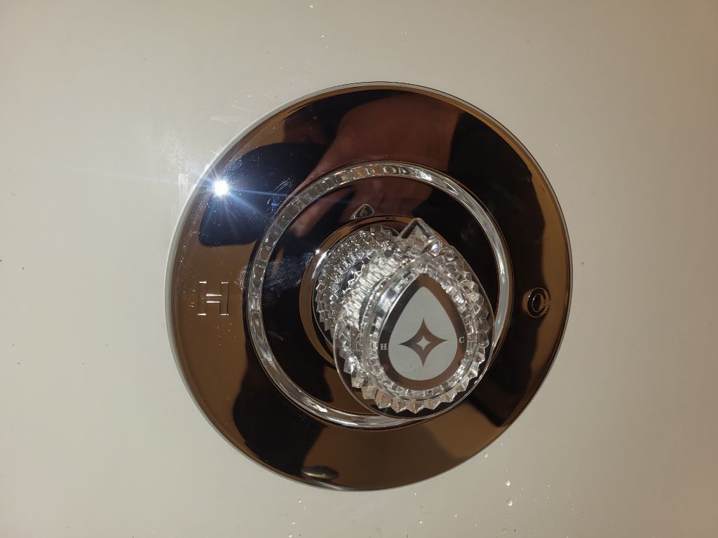 A close up of a faucet with a water drop on it