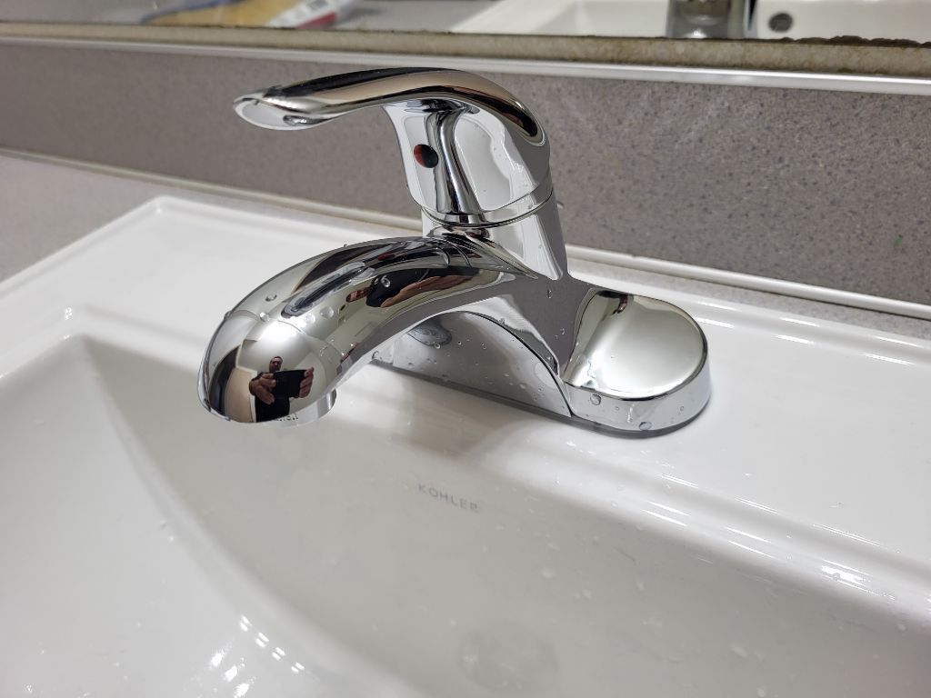 A bathroom sink with a chrome faucet and a mirror