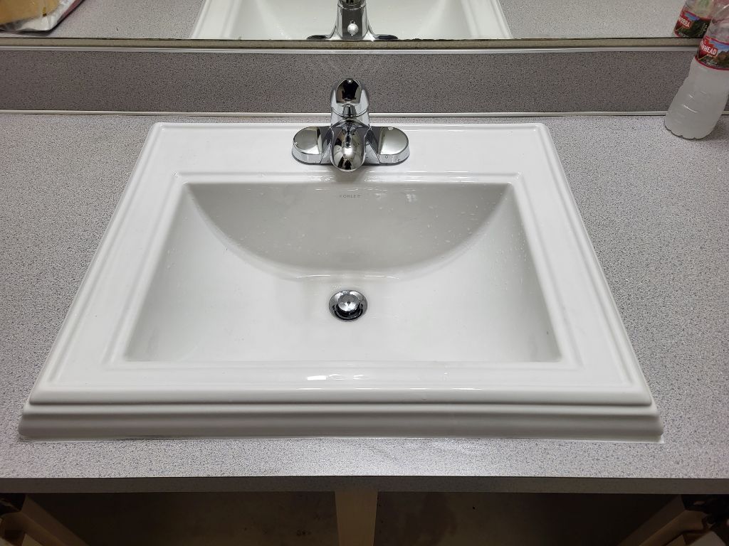 A bathroom sink with a faucet and a mirror