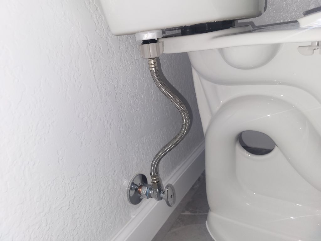 Flexible metal toilet supply hose connected to a toilet tank and wall shutoff valve