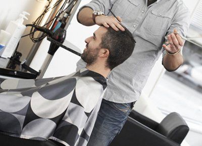 A man is getting his hair cut by a hairdresser in a salon.