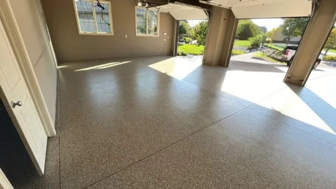 A newly coated garage floor with sunlight shining in, viewed from inside.