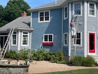 A house with a green porch and a white picket fence