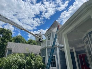 A man is painting the roof of a house with a crane.