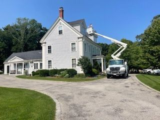 A white truck is parked in front of a large white house.