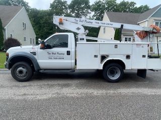 A white utility truck with a crane on the back is parked in front of a house.