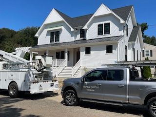 Two trucks are parked in front of a large white house.
