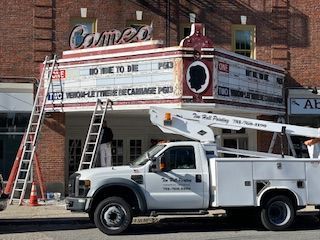 A white truck is parked in front of a cameo theater