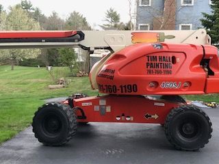 A red lift with the words tim hall painting on it is parked in a driveway.