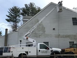 A white truck with a crane on the back is parked in front of a house.