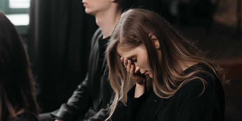 A woman is crying while sitting next to a man in a dark room.