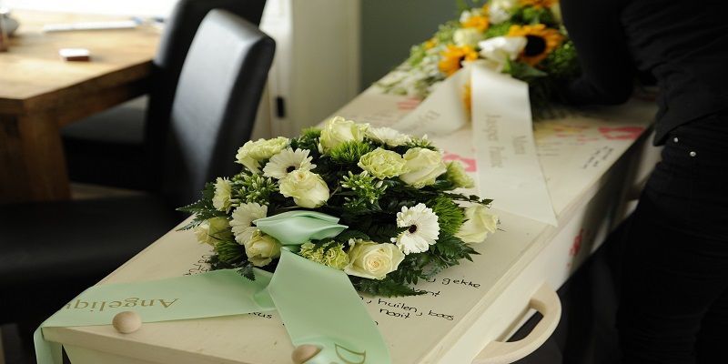 A coffin with flowers on it is sitting on a table.