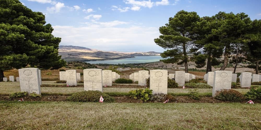 A cemetery with a view of the ocean and mountains in the background.
