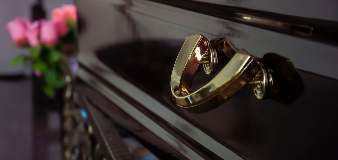 A close up of a gold handle on a black coffin.