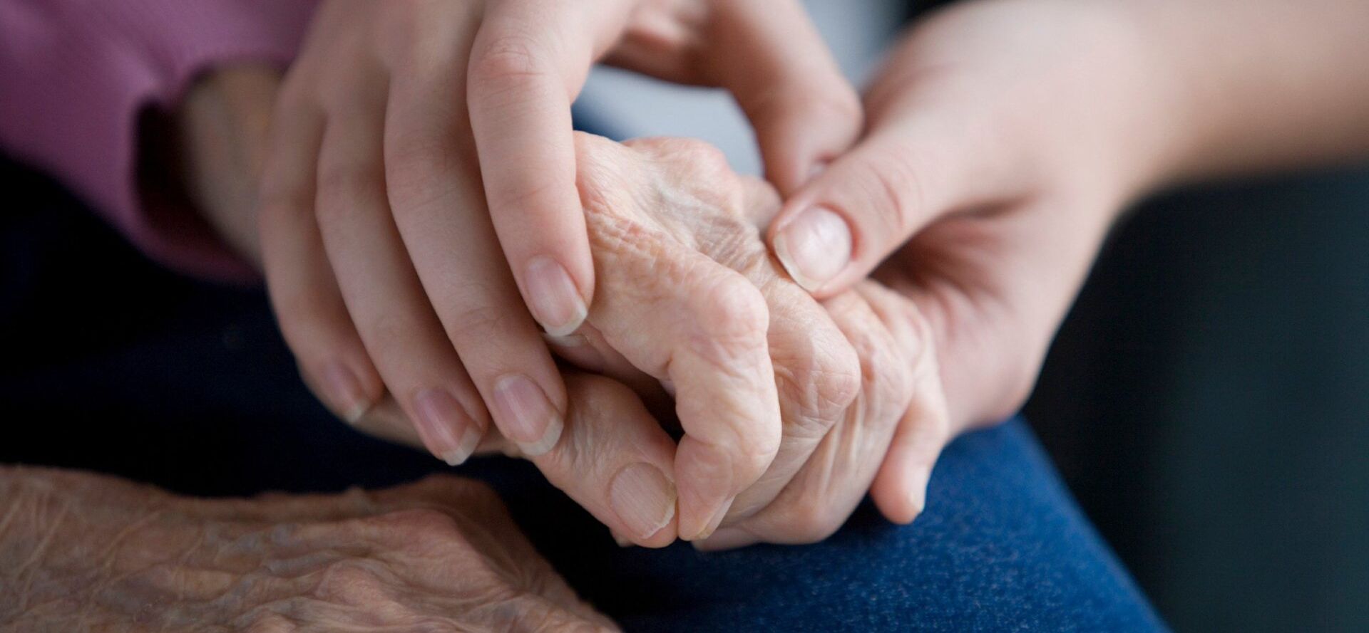 A woman is holding the hand of an older woman.