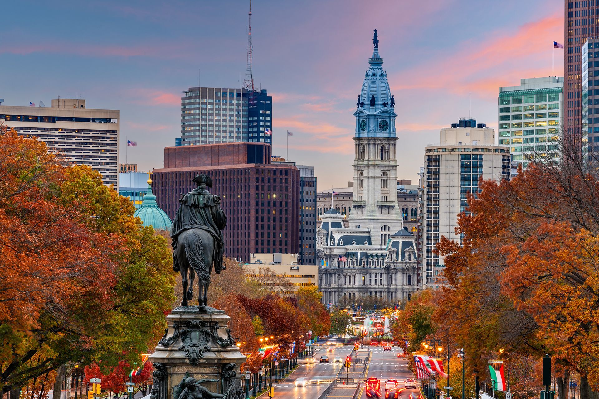 A statue of a man on a horse in front of a city skyline.