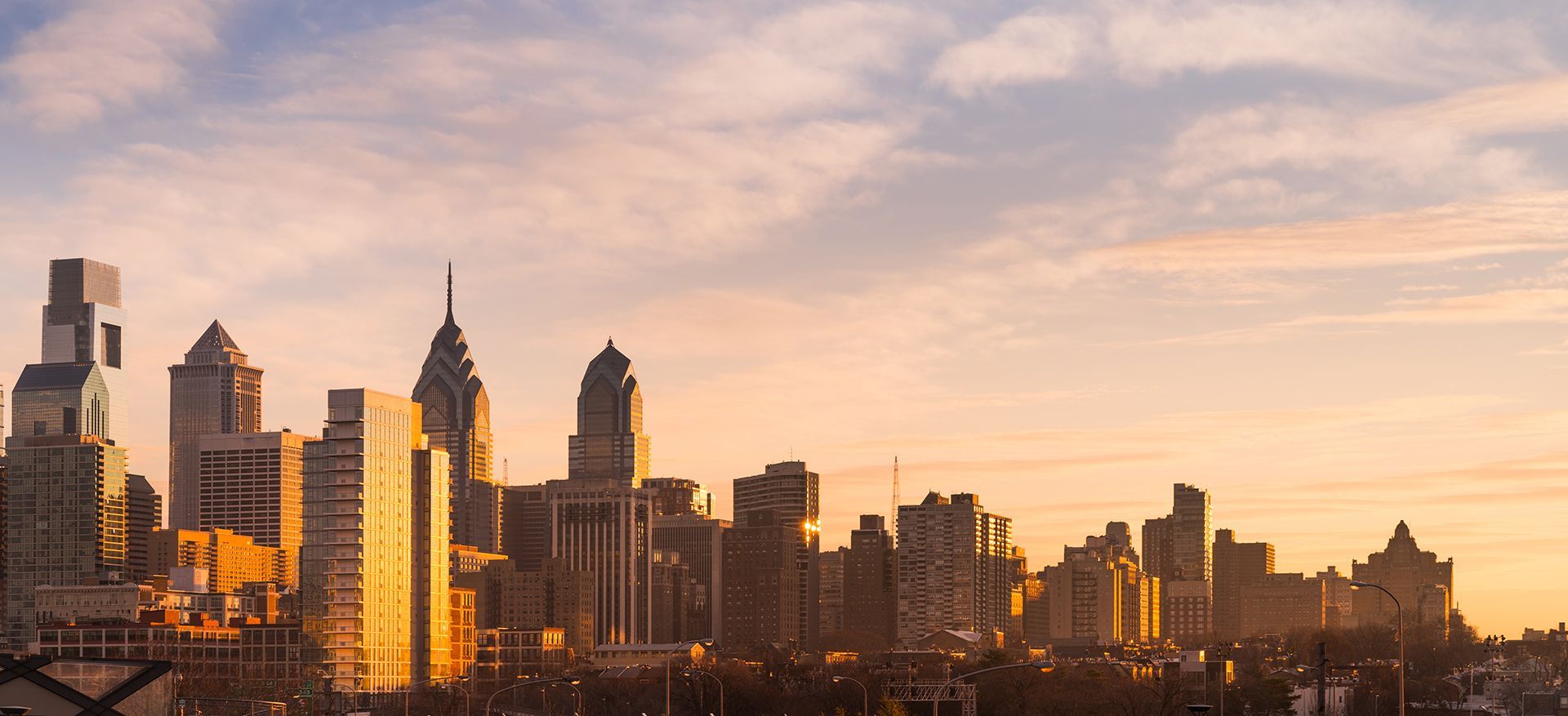 A city skyline at sunset with a bridge in the foreground.