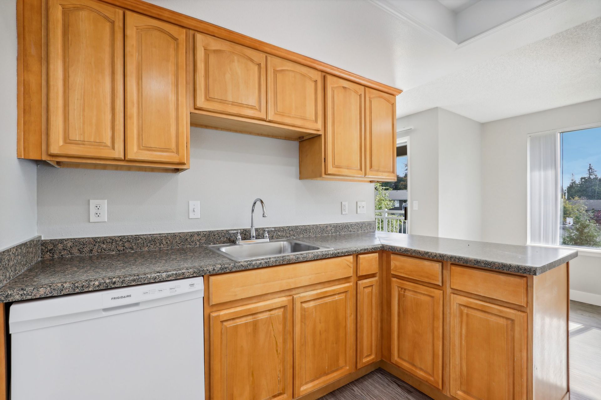 Kitchen with warm wooden cabinets, granite countertops, and a stainless steel sink.