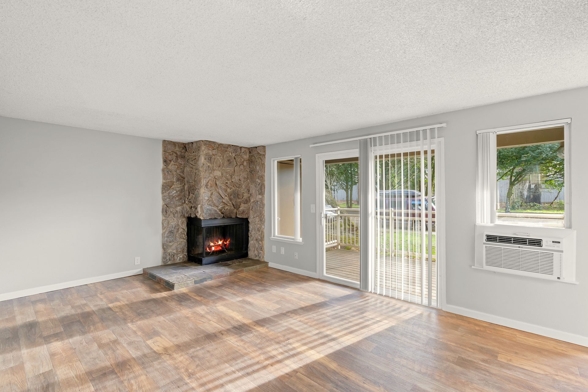 Hardwood style flooring throughout bright, large living room with fireplace
