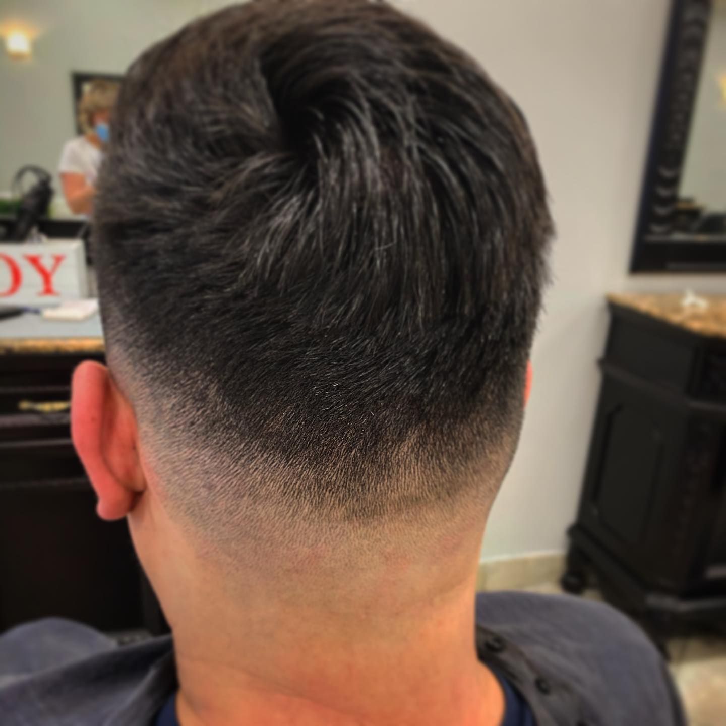 Man's back of the head with a dark fade haircut.