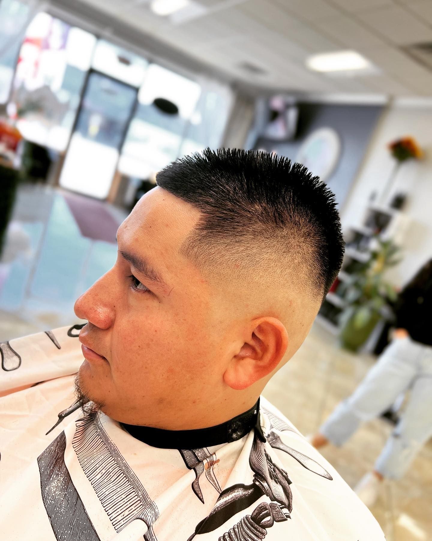 Man with a faded haircut, side profile view, in a hair salon.