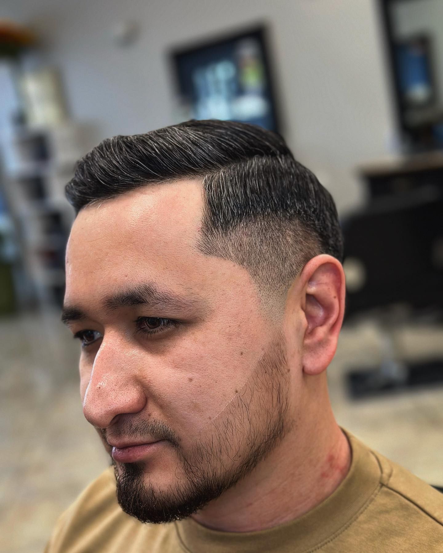 Man with a fade haircut, looking to the side, in a barbershop.