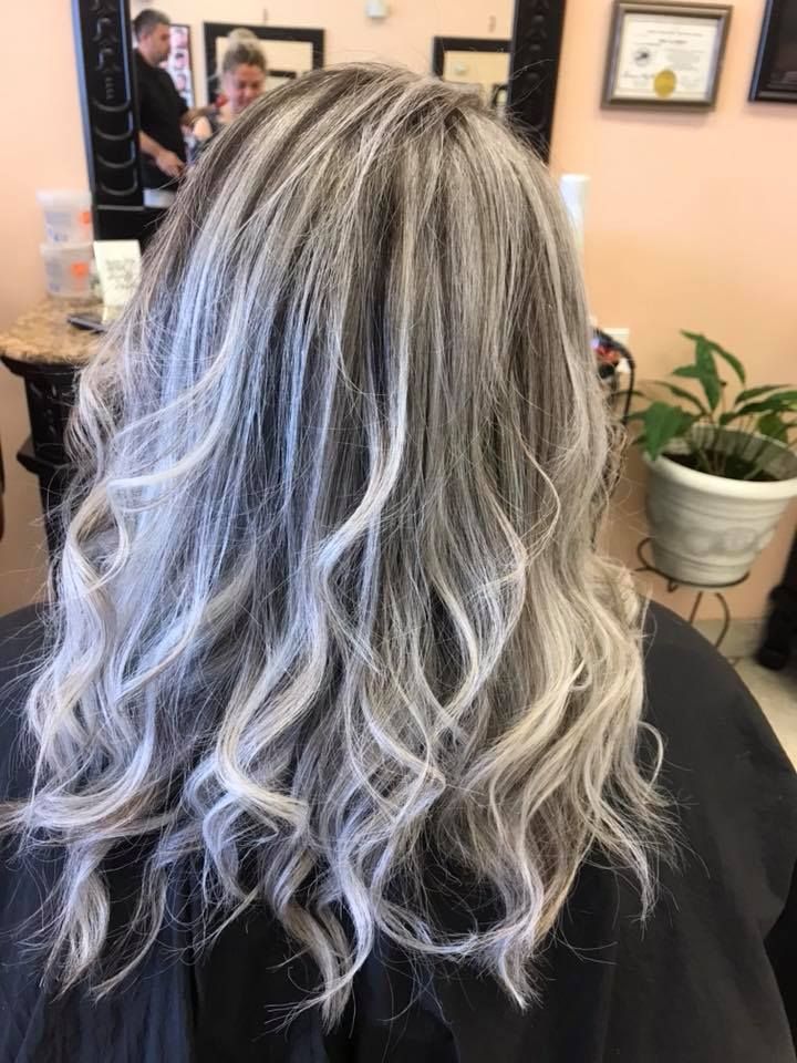Woman with long, wavy gray and silver hair in a salon setting.