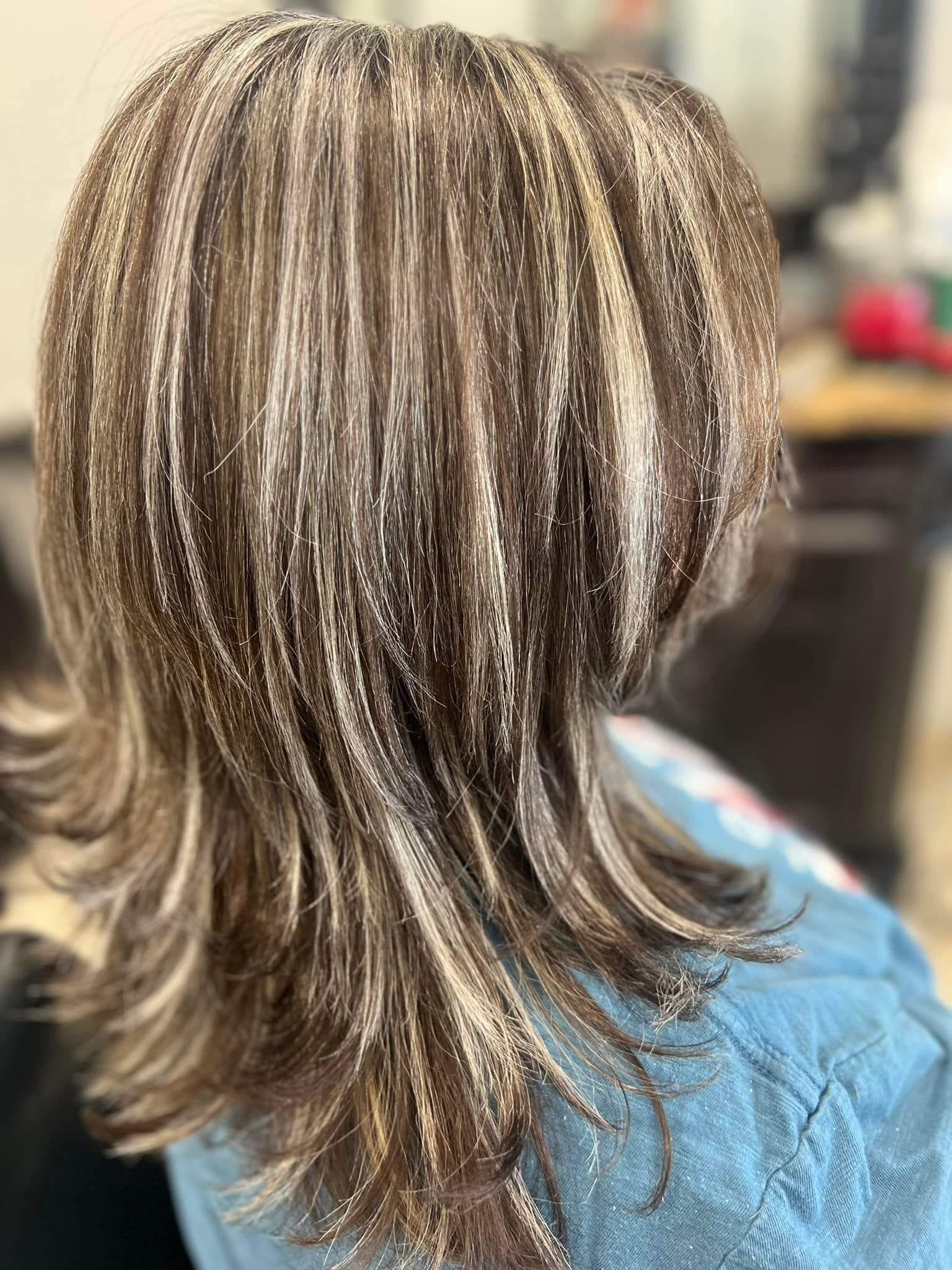 Woman's hair styled with highlights. Brown hair with streaks of blonde, styled at a salon.