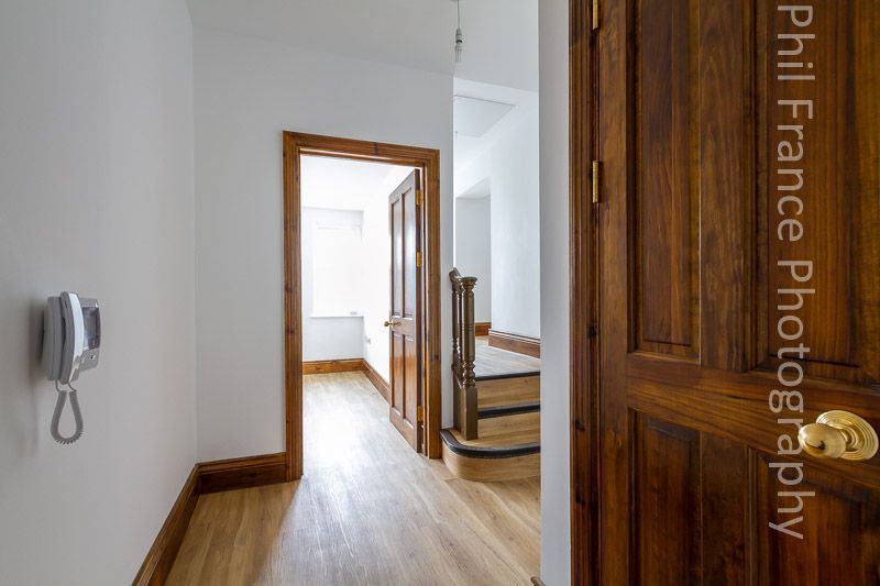 Bright hallway with wooden doors, light wood floor, and staircase leading to a sunlit room