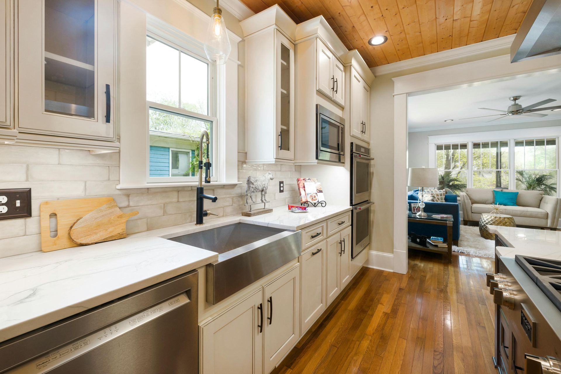 a kitchen with mainly white and marble colours but wooden flooring and ceiling