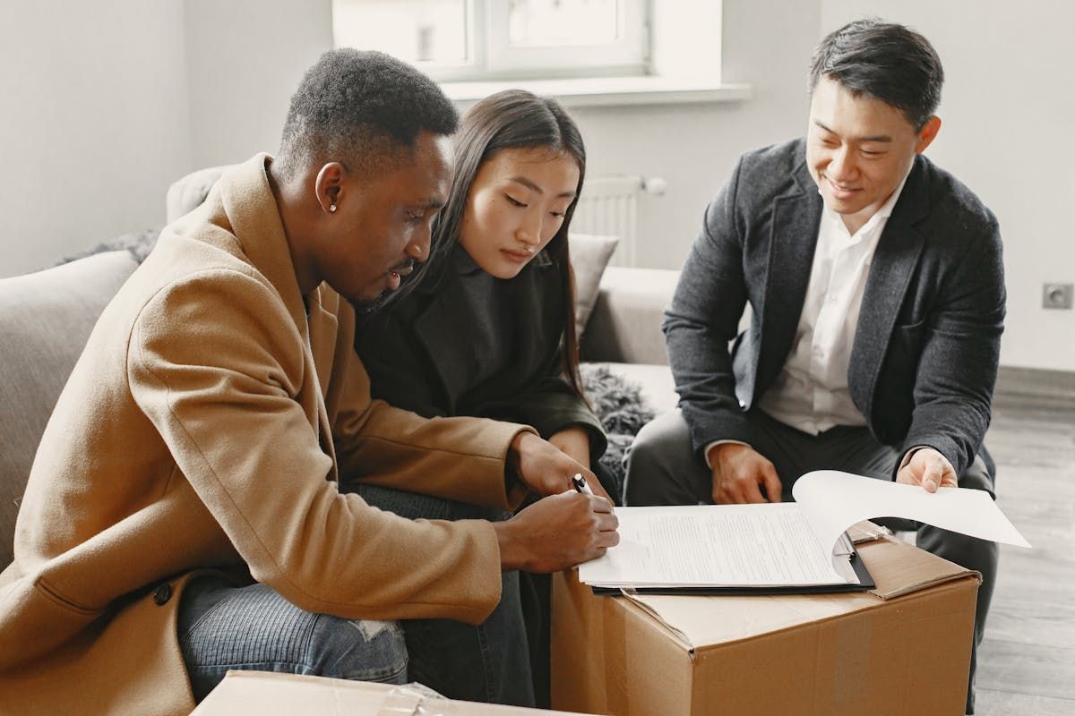 people holding model house while looking at charts