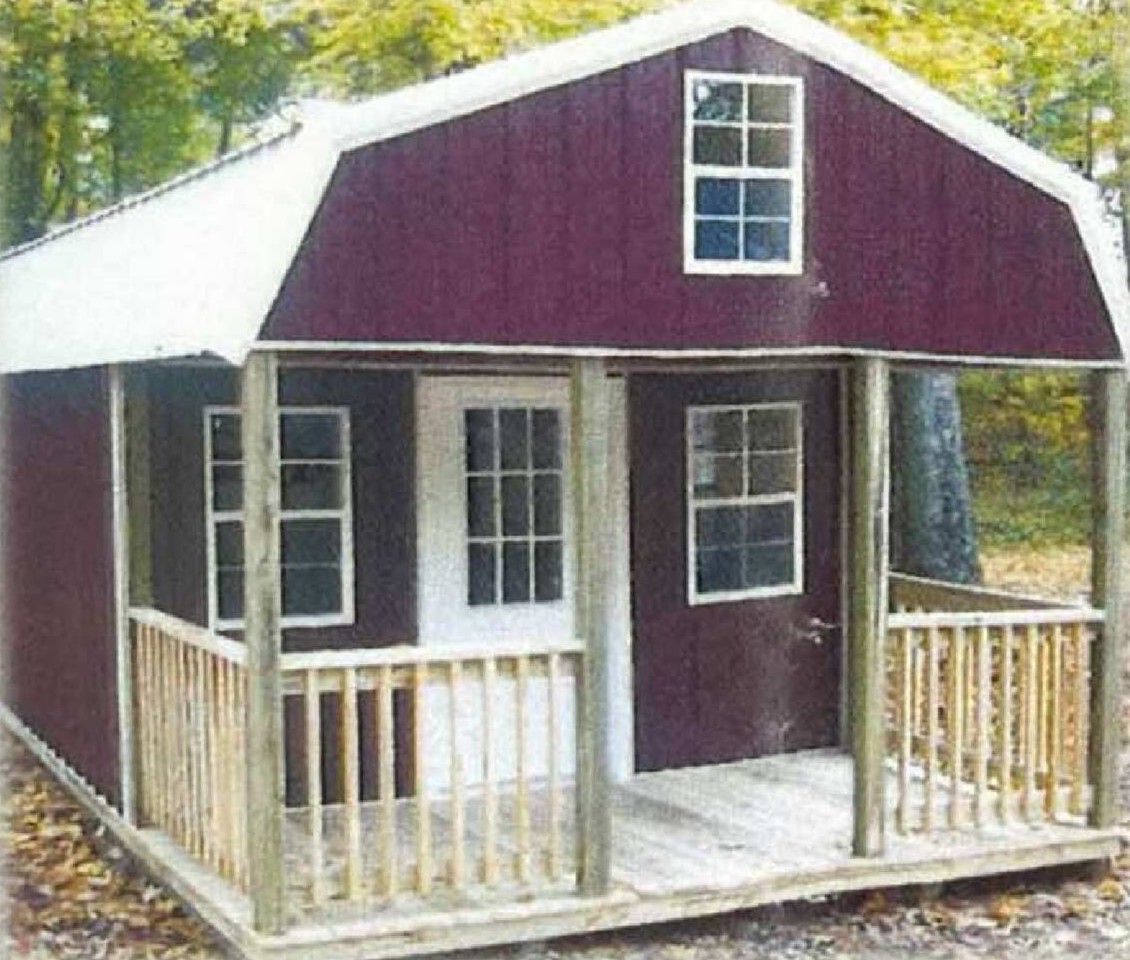 Small red-and-white wooden playhouse with porch and railings in a wooded outdoor setting