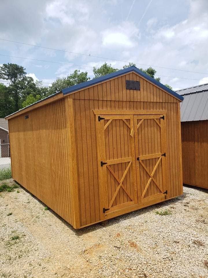 Wooden outdoor shed with double barn doors and a peaked roof on a gravel lot