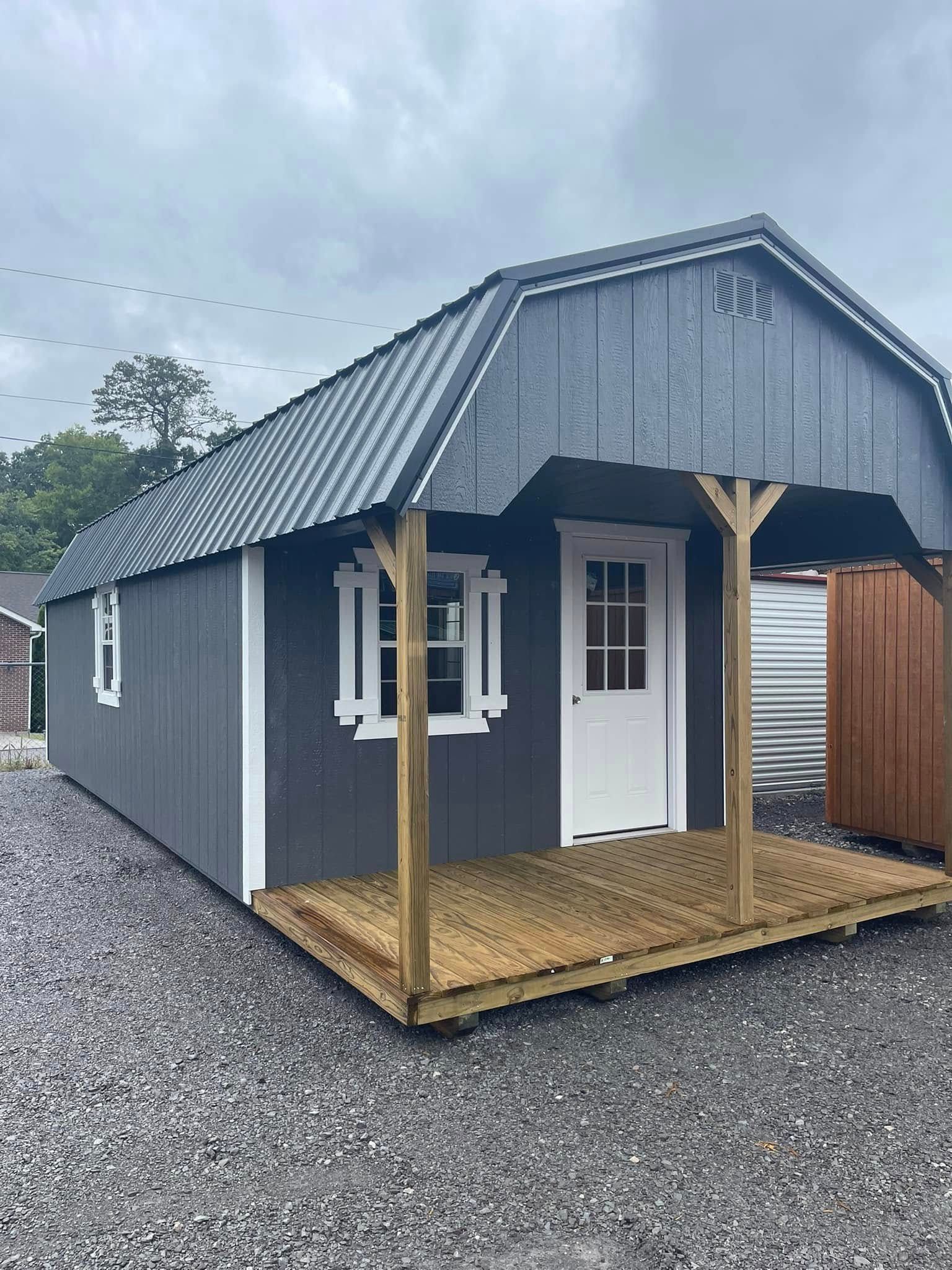Small gray cabin with a metal roof, white trim, and a front porch on gravel.