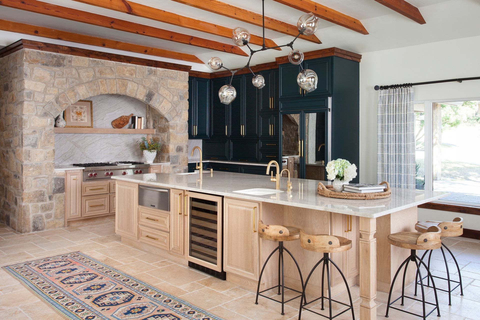 A kitchen with a large island , stools and a refrigerator.