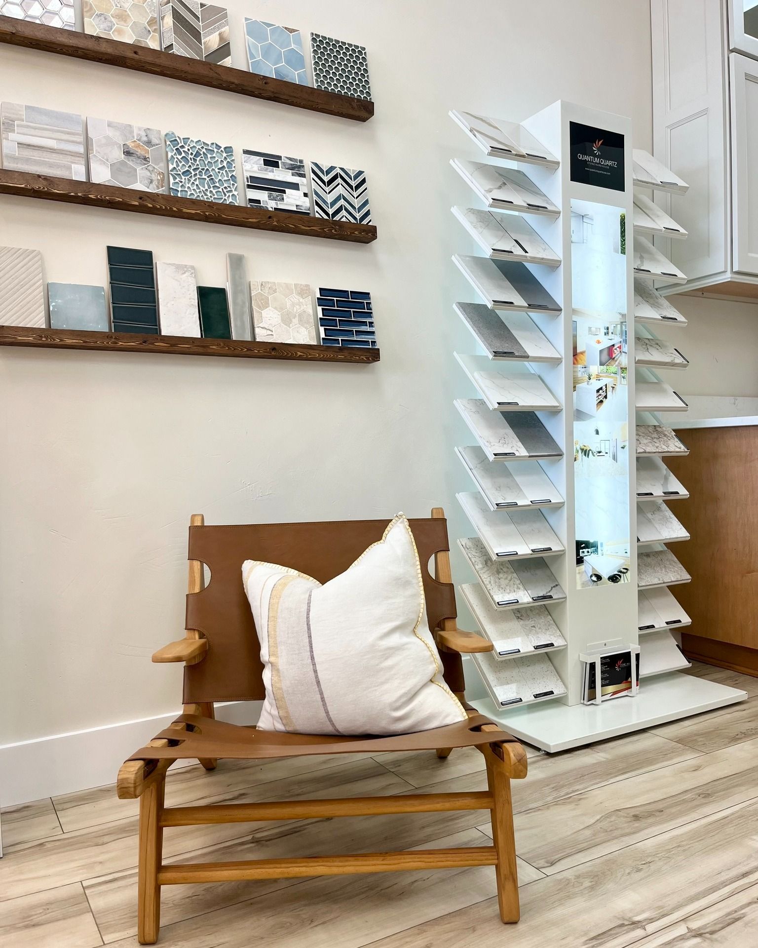A chair with a white pillow on it is sitting in a room next to a tile display.