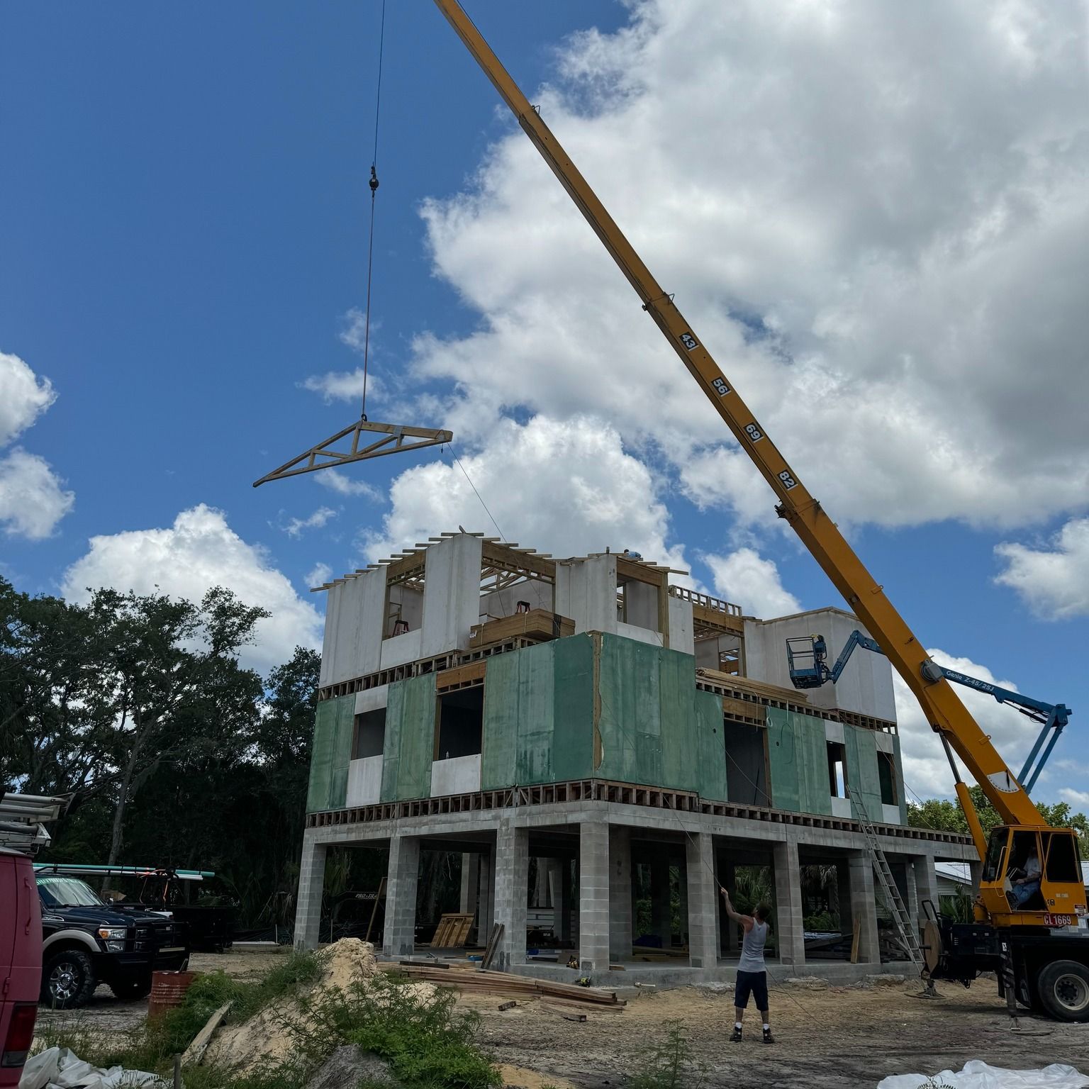 A large crane is lifting a beam over a building under construction