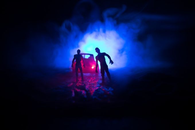 Two silhouetted figures in red and blue light in a dark, smoky scene