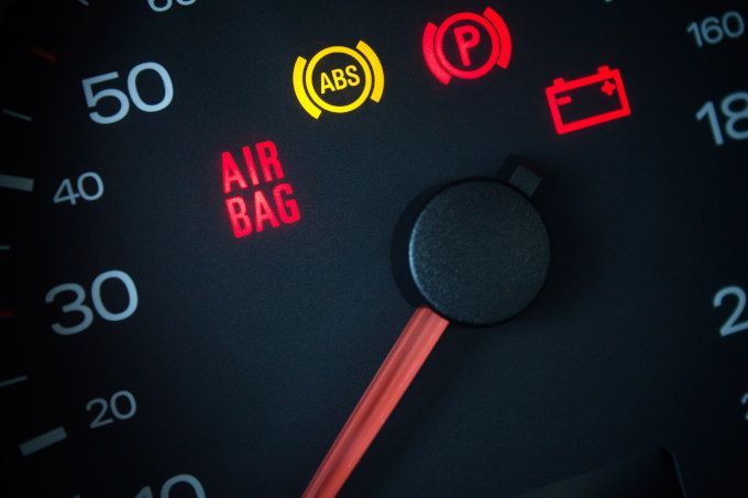 Car dashboard warning lights lit up around the speedometer and gauge needle