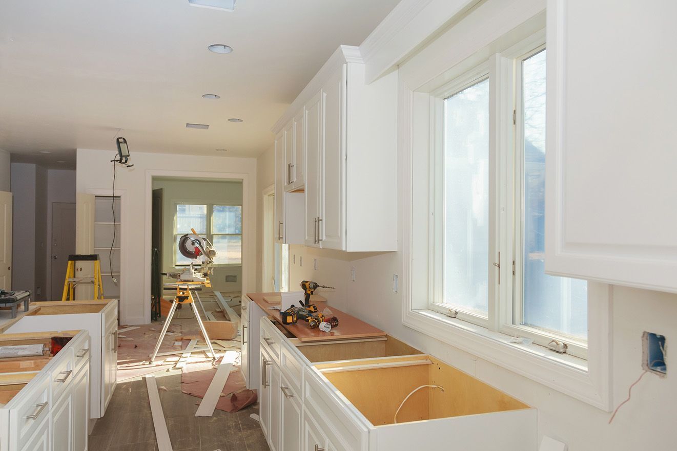 A kitchen under construction with white cabinets and a sink.