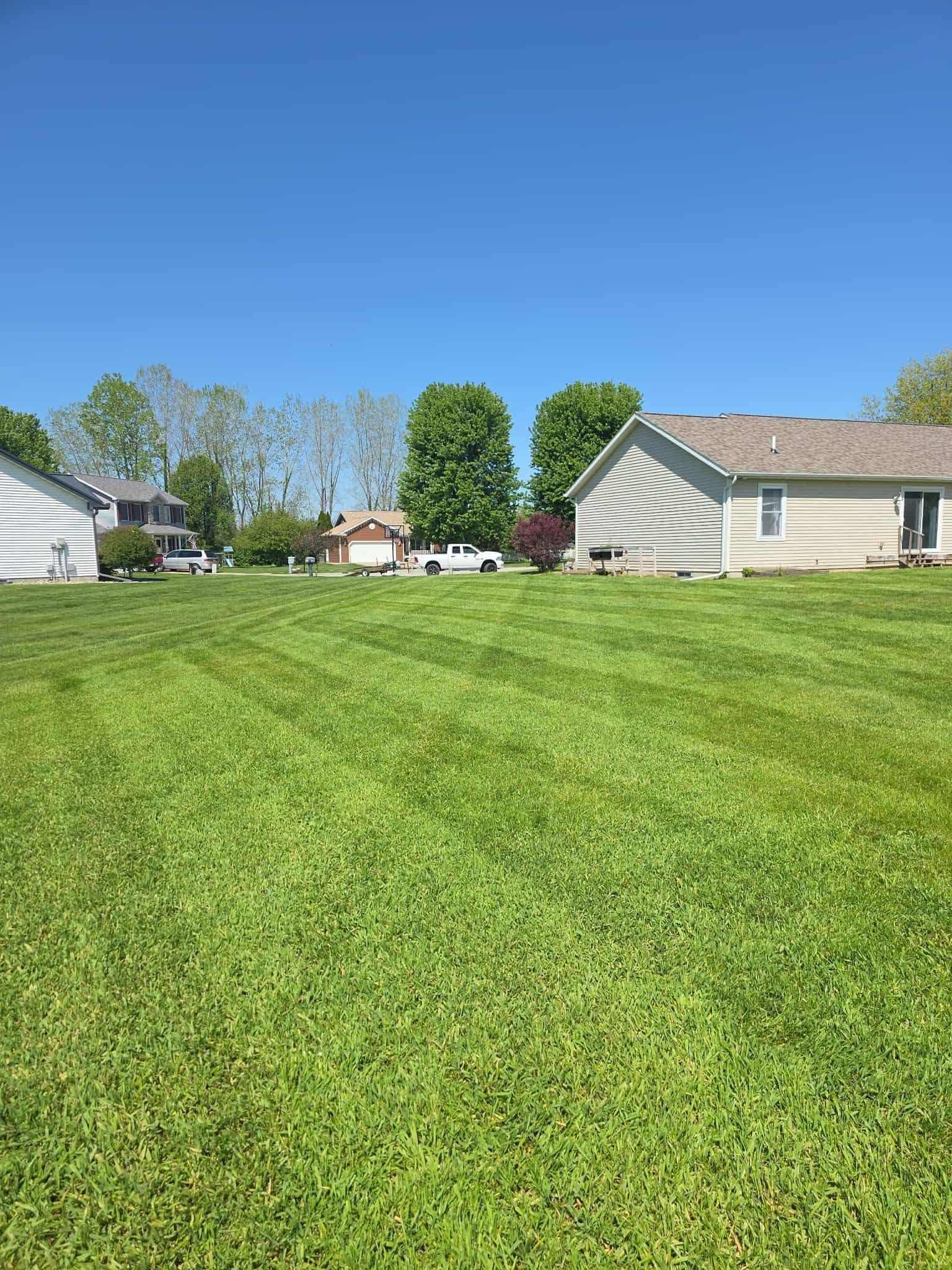 Suburban houses beyond a wide green lawn under a clear blue sky