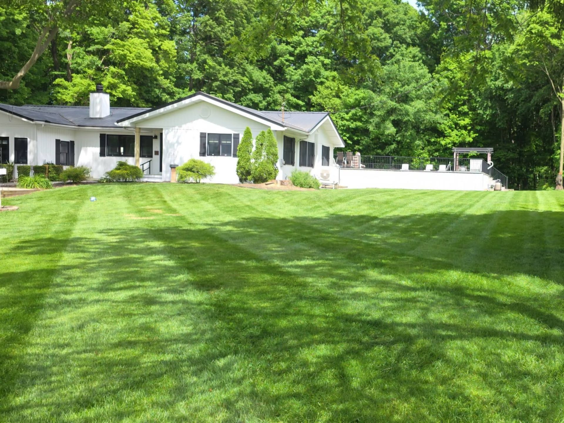 White house with a large green lawn and trees in the background.