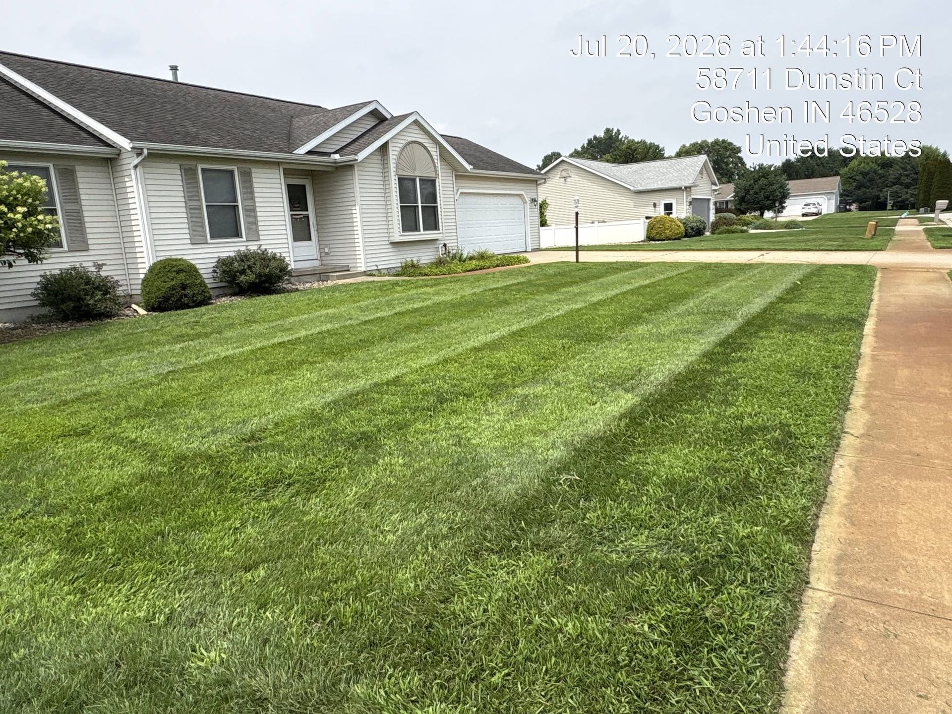 Suburban house with neatly mowed lawn and a driveway under a cloudy sky