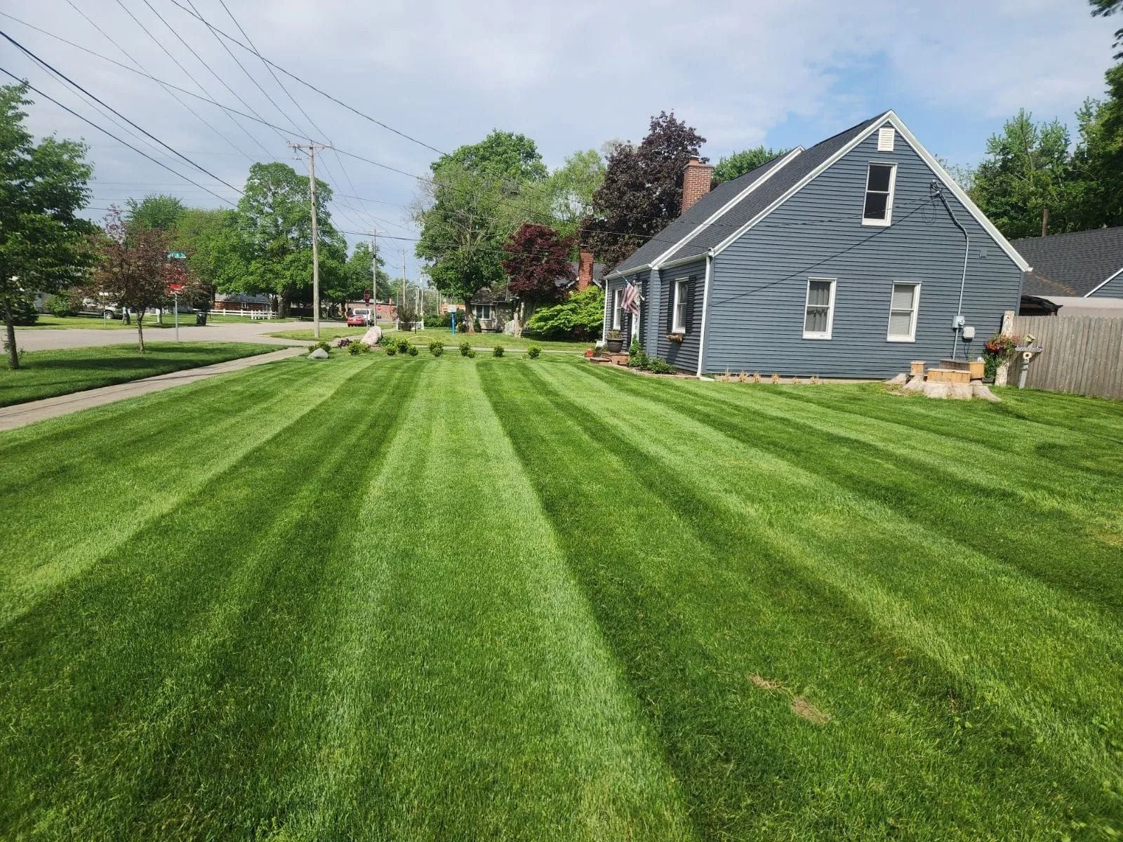 Freshly mowed green lawn beside a blue house in a suburban neighborhood