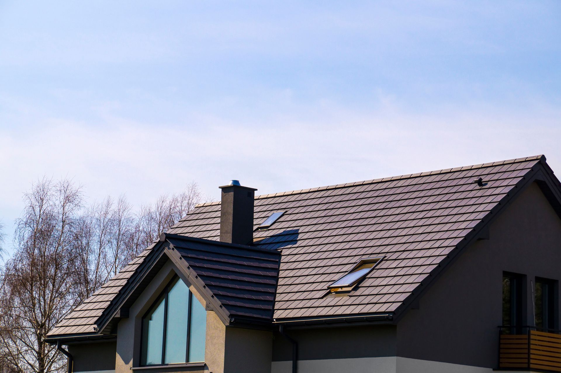 Modern house roof with skylights and a chimney under a blue sky Modern house roof with skylights and a chimney under a blue sky